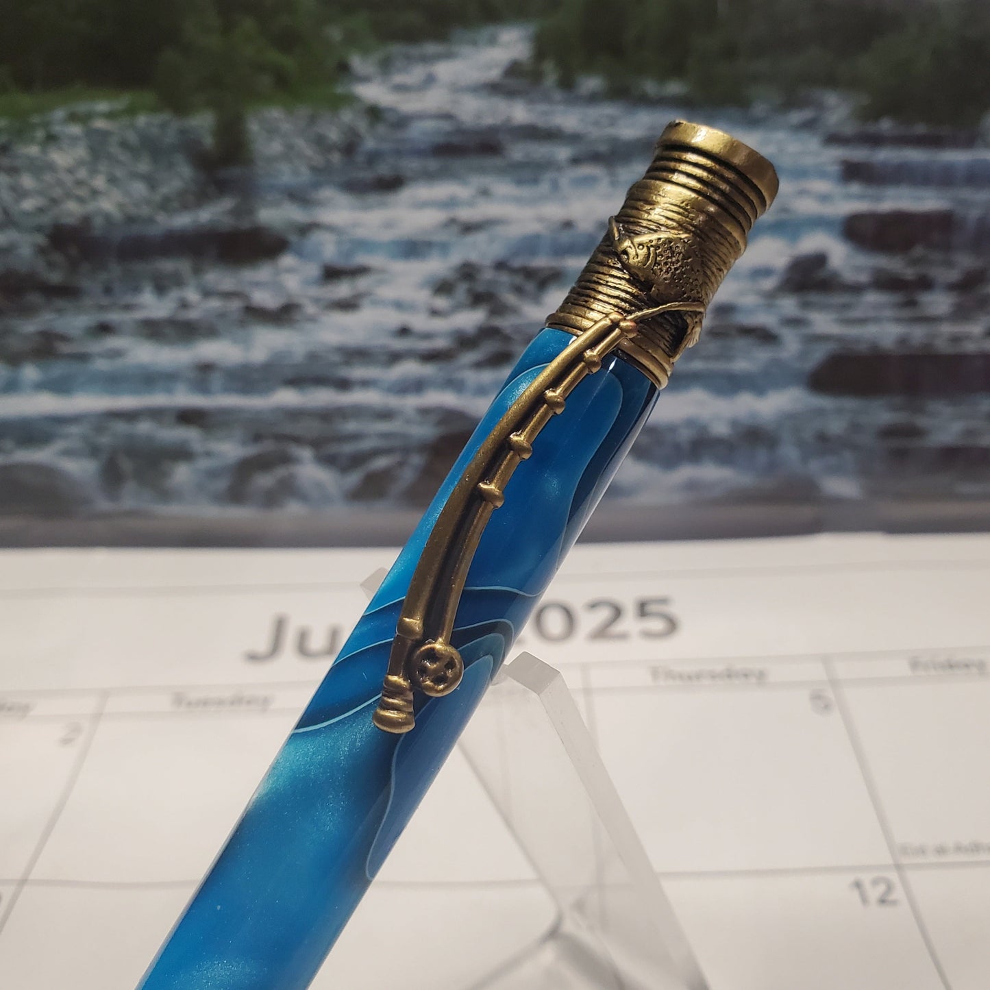 Top of Flyfishing writing pen featuring a clip that resembles a fishing pole and a cap with an engraving of a fish