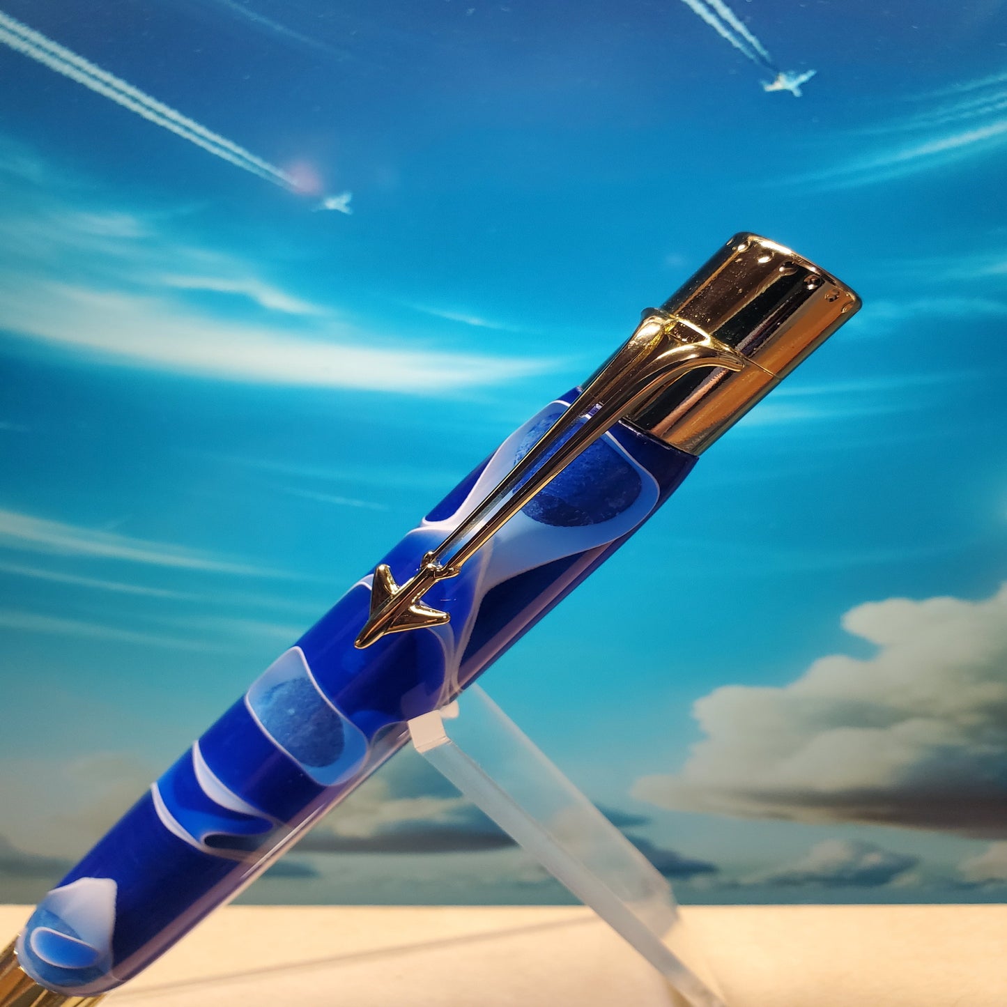 Close-up of the top of the Jetliner writing pen featuring a gold clip designed to look like a jet airliner with  jet trails