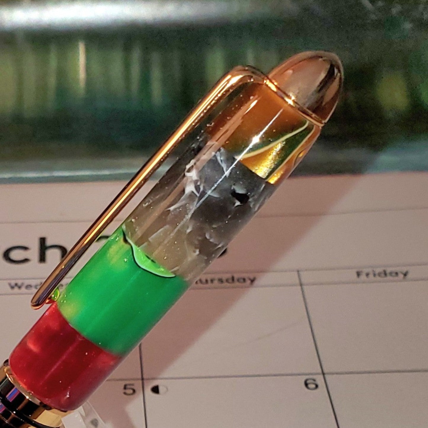 Close-up of the top of he potpourri pen featuring a gold clip, cap and a variety of colors